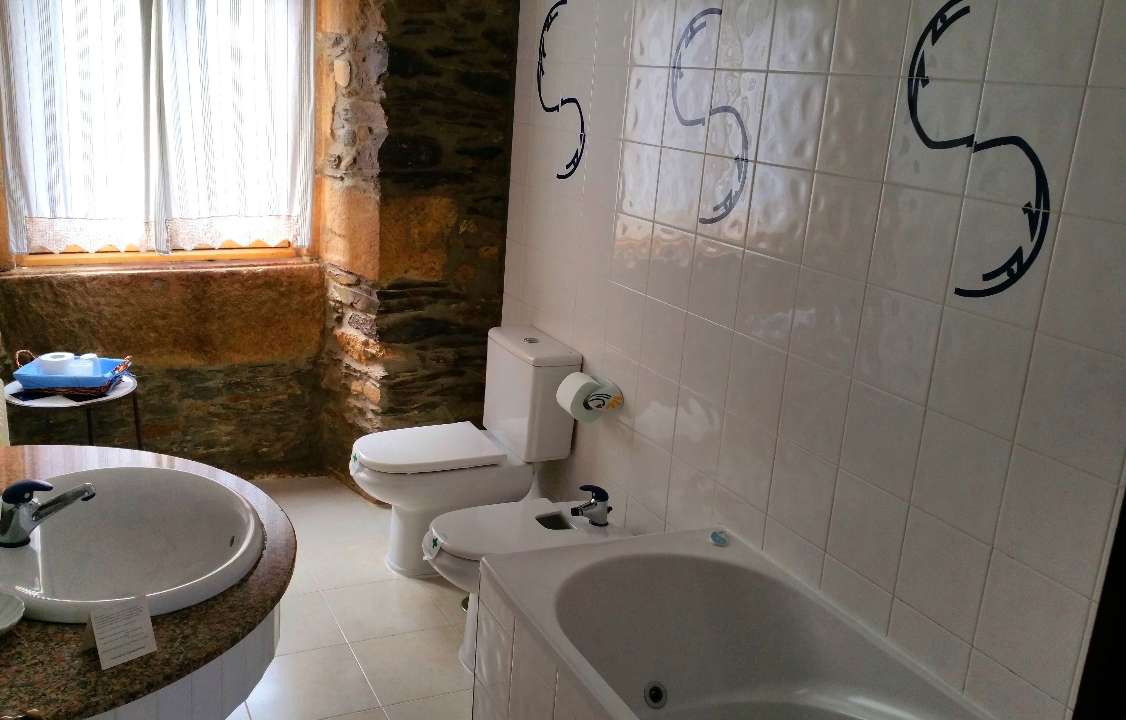 Un baño con pared de piedra, un lavabo, un inodoro y una bañera.