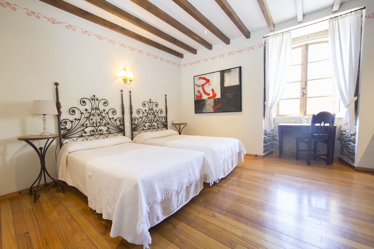 A bedroom with two beds, a desk, and a chair.