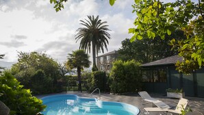 A swimming pool with lounge chairs and a stone building in the background. - Pazo da Trave (Viveiro)