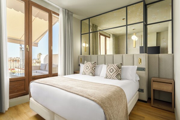 Ein Hotelzimmer mit einem großen Bett, einem Nachttisch, einem Spiegel und Blick auf den Balkon.