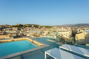 A rooftop pool area with clear views of a cityscape, including buildings and a hill with a castle-like structure. - Room Mate Leo, Granada (Granada)