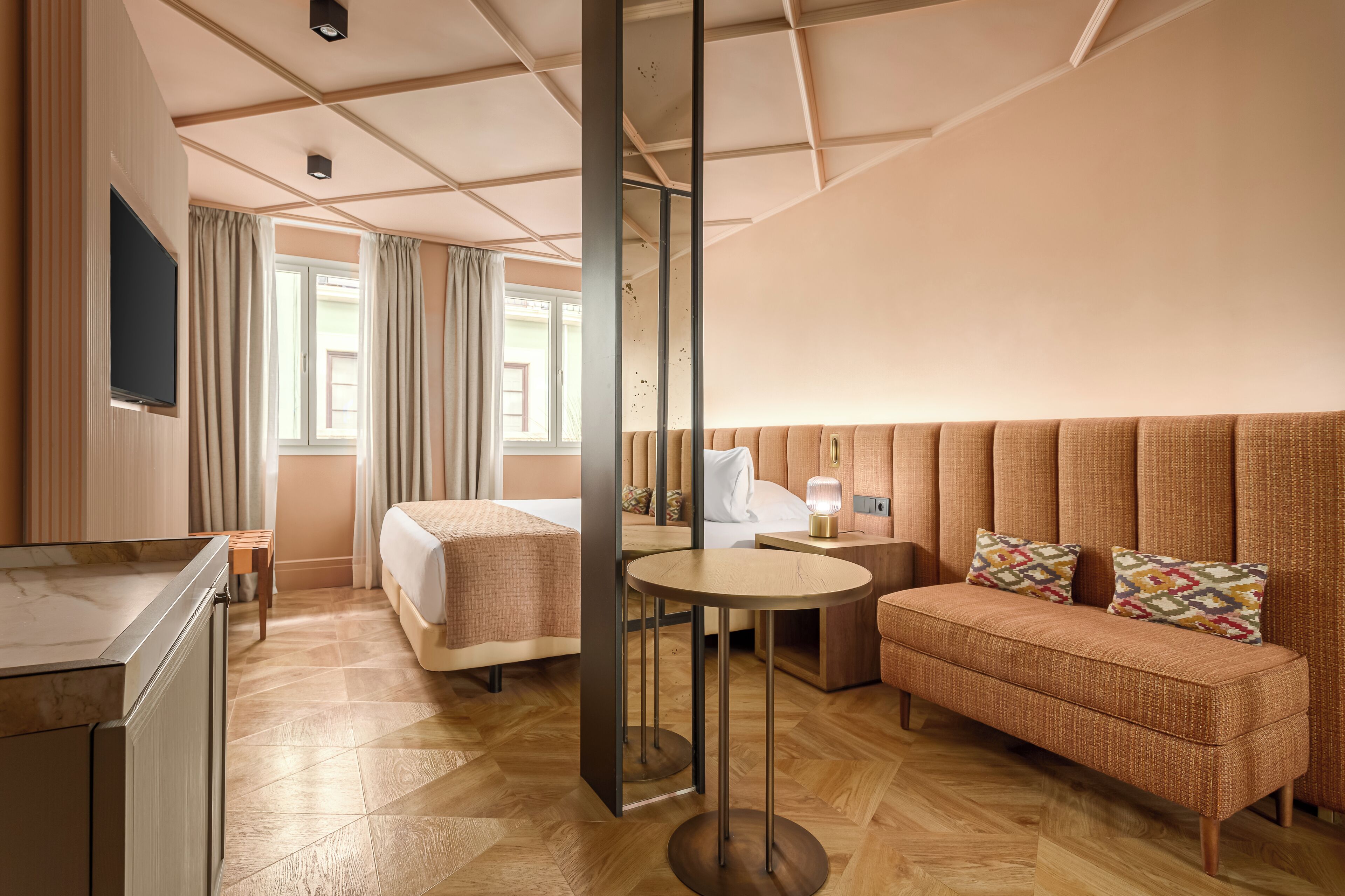 A hotel room with a bed, a sofa, a small table, and a TV.