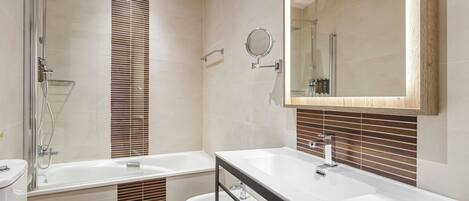 A modern bathroom with a glass-enclosed shower, a double sink vanity, and a toilet.