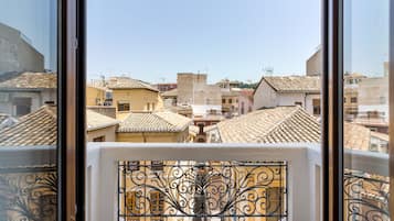 Vista desde una ventana con barandillas de hierro ornamentales, sobre una zona urbana densamente poblada con tejados y edificios de estilo tradicional.