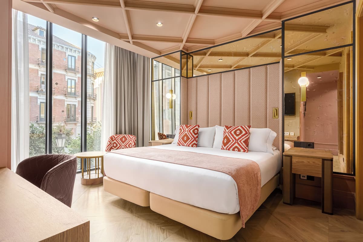 Ein modernes Hotelzimmer mit einem großen Bett, einem Schreibtisch und Blick auf die Stadt.