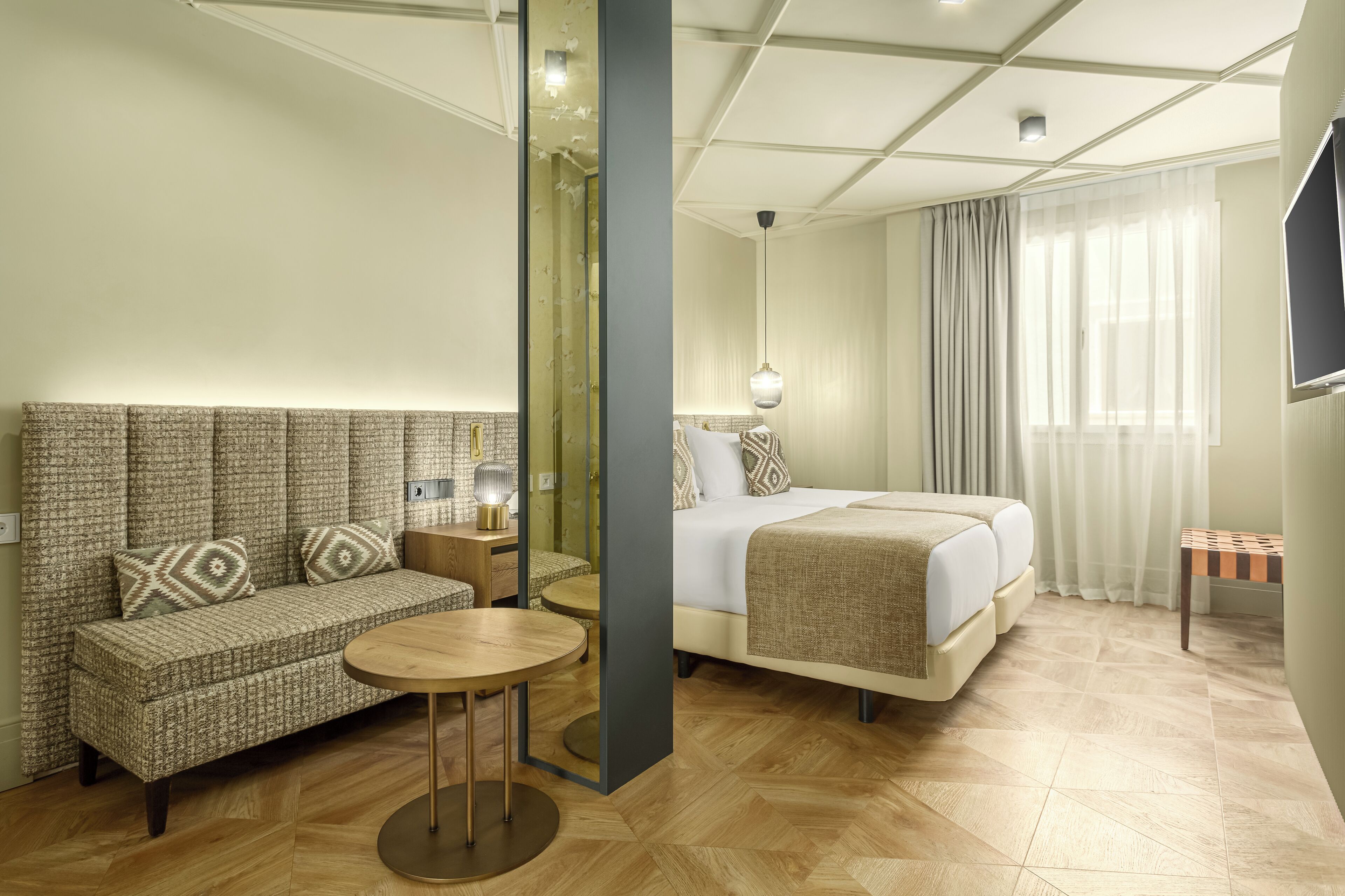 Habitación de hotel con sofá, una mesa redonda, cama y televisor.
