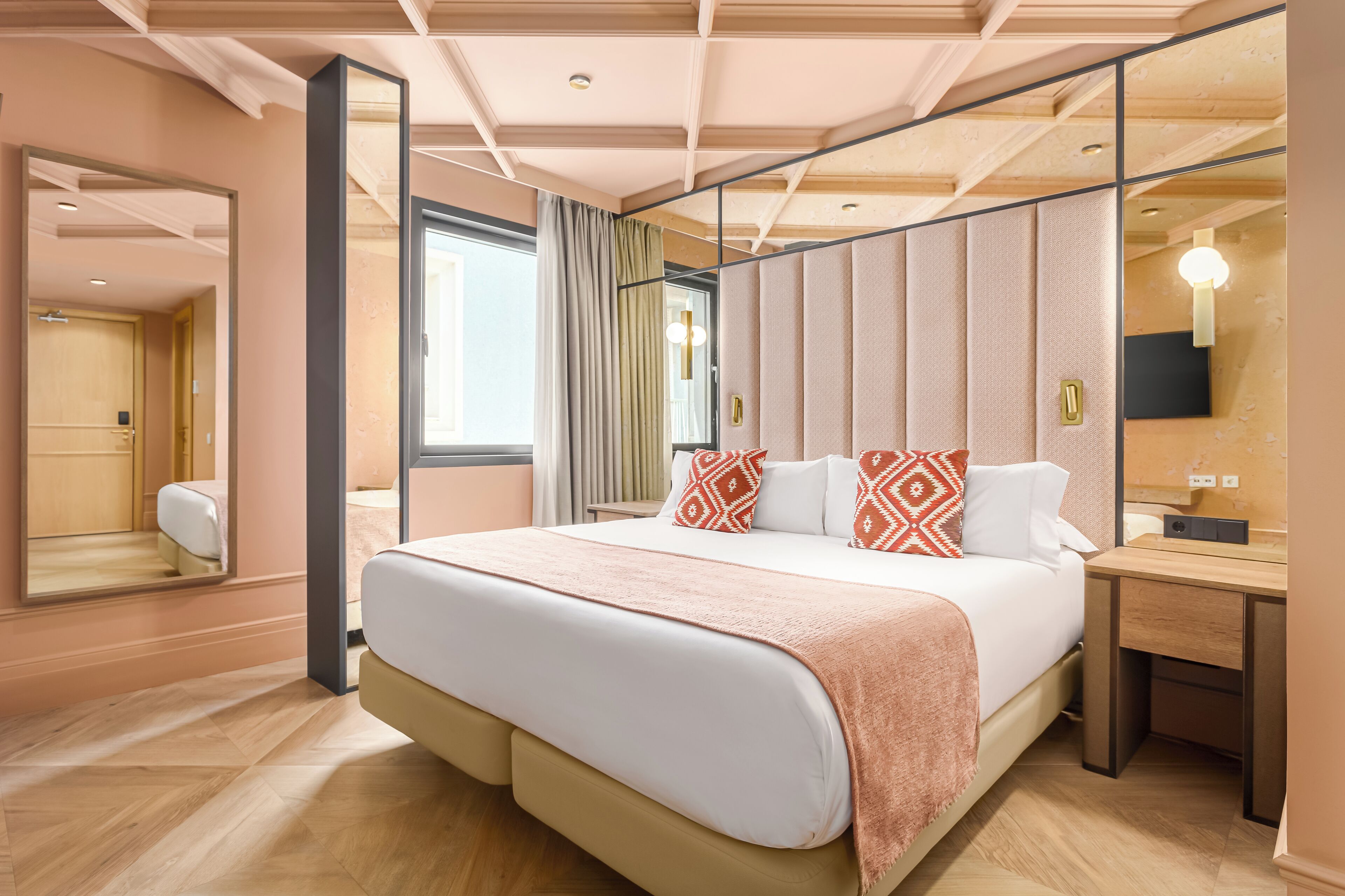 Een moderne hotelkamer met een groot bed, een nachtkastje, een spiegel en uitzicht op de badkamer.