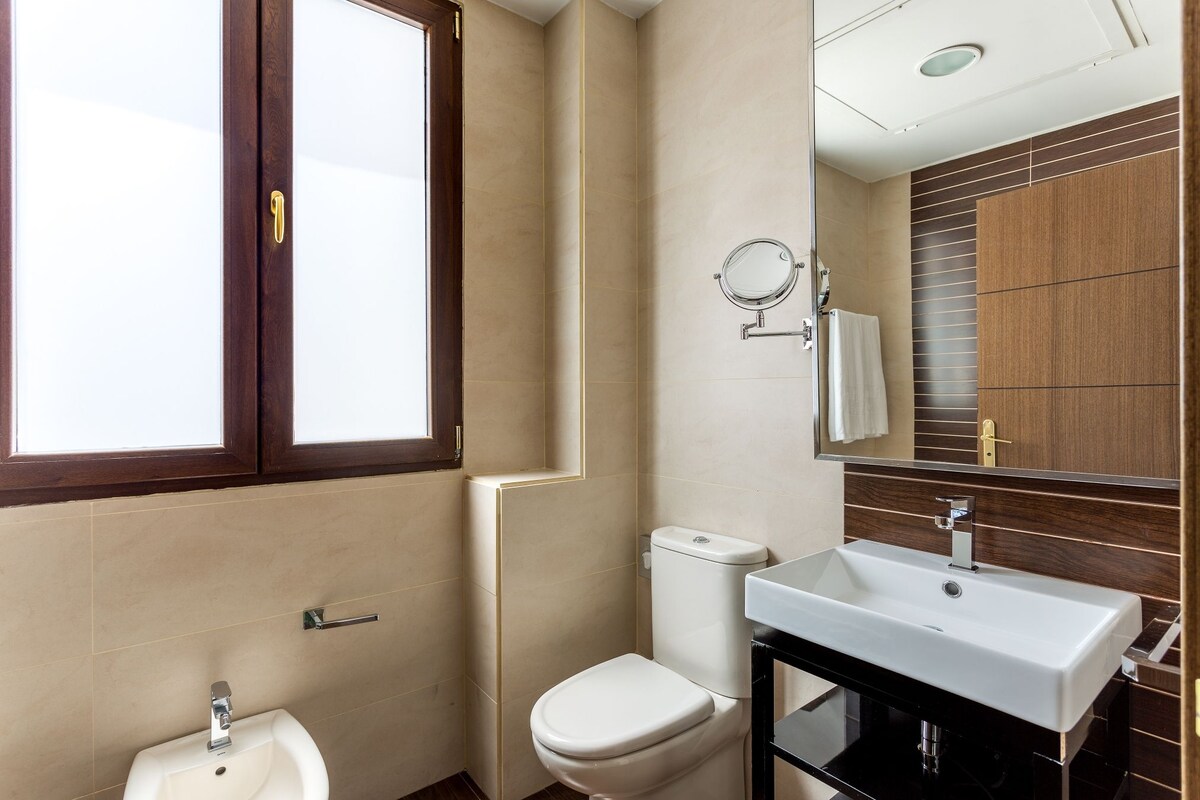 A modern bathroom with a toilet, sink, and mirror.