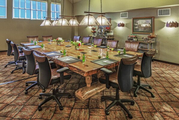 A conference room with a large wooden table, leather chairs, and a chandelier.