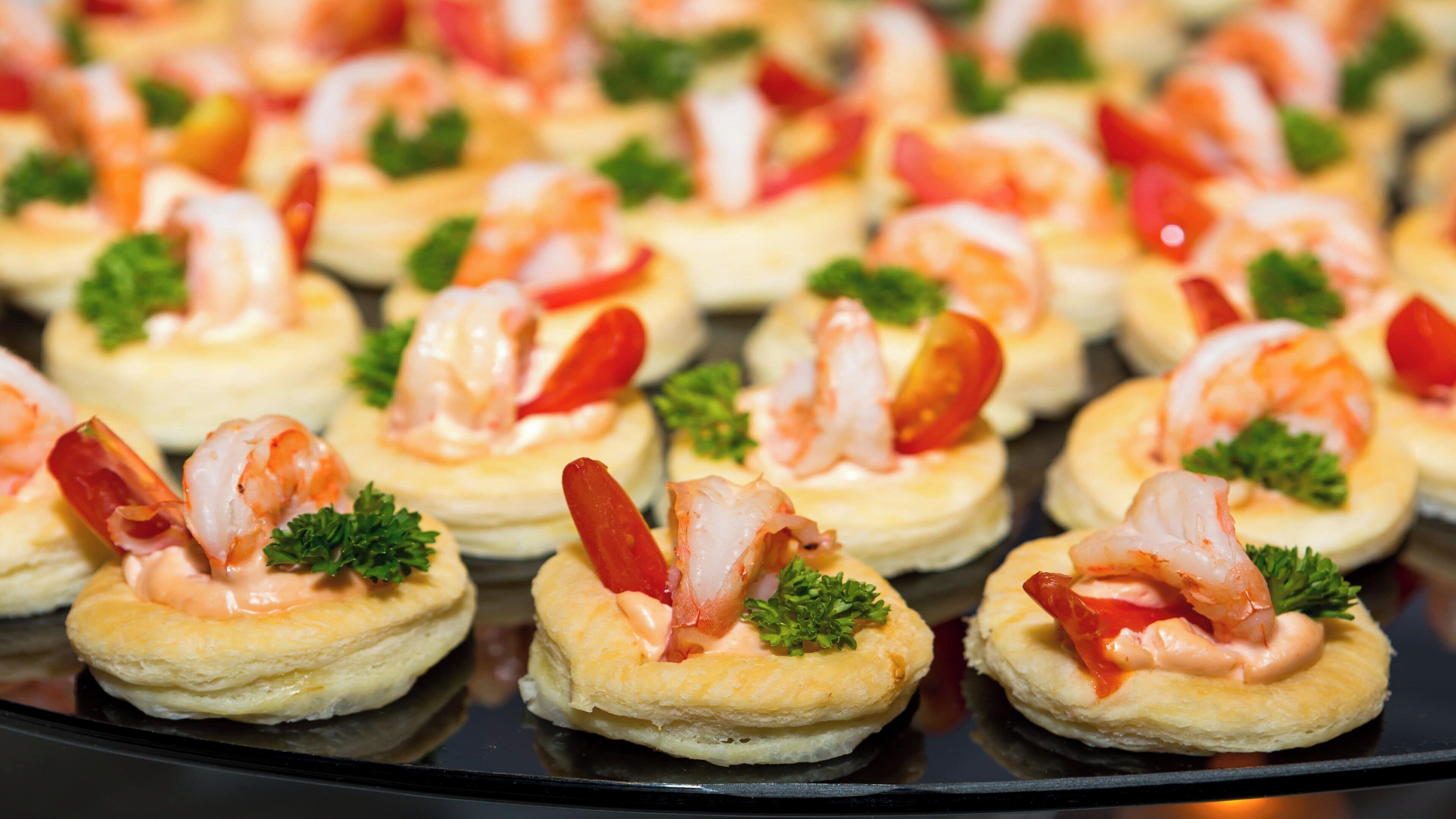 A tray of appetizers with shrimp and garnishes.