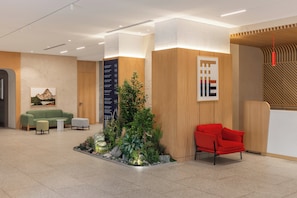 A modern reception area with a green sofa, red chair, and a small indoor garden.