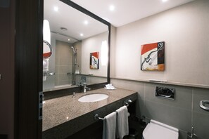 A modern bathroom with a granite sink, a large mirror, and a toilet.