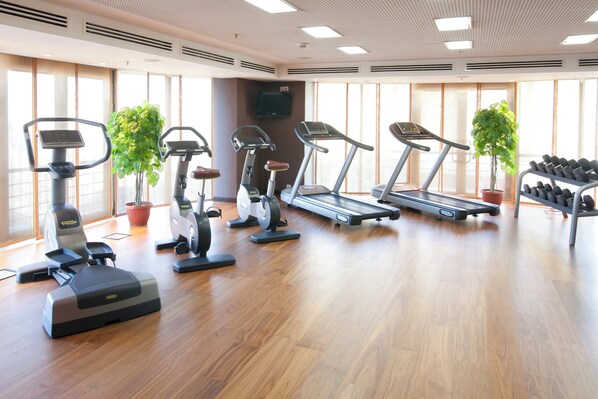 A gym with various exercise equipment including treadmills, stationary bikes, and a rowing machine.