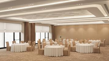 Un salón de conferencias con varias mesas redondas, sillas color crema y piso alfombrado.