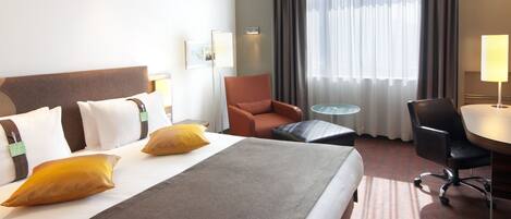 Una camera d'albergo con un letto grande, una scrivania, una sedia e un tavolino.