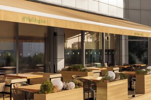 An outdoor seating area with wooden tables and chairs, some with planters. - Holiday Inn ALMATY by IHG (Almaty)