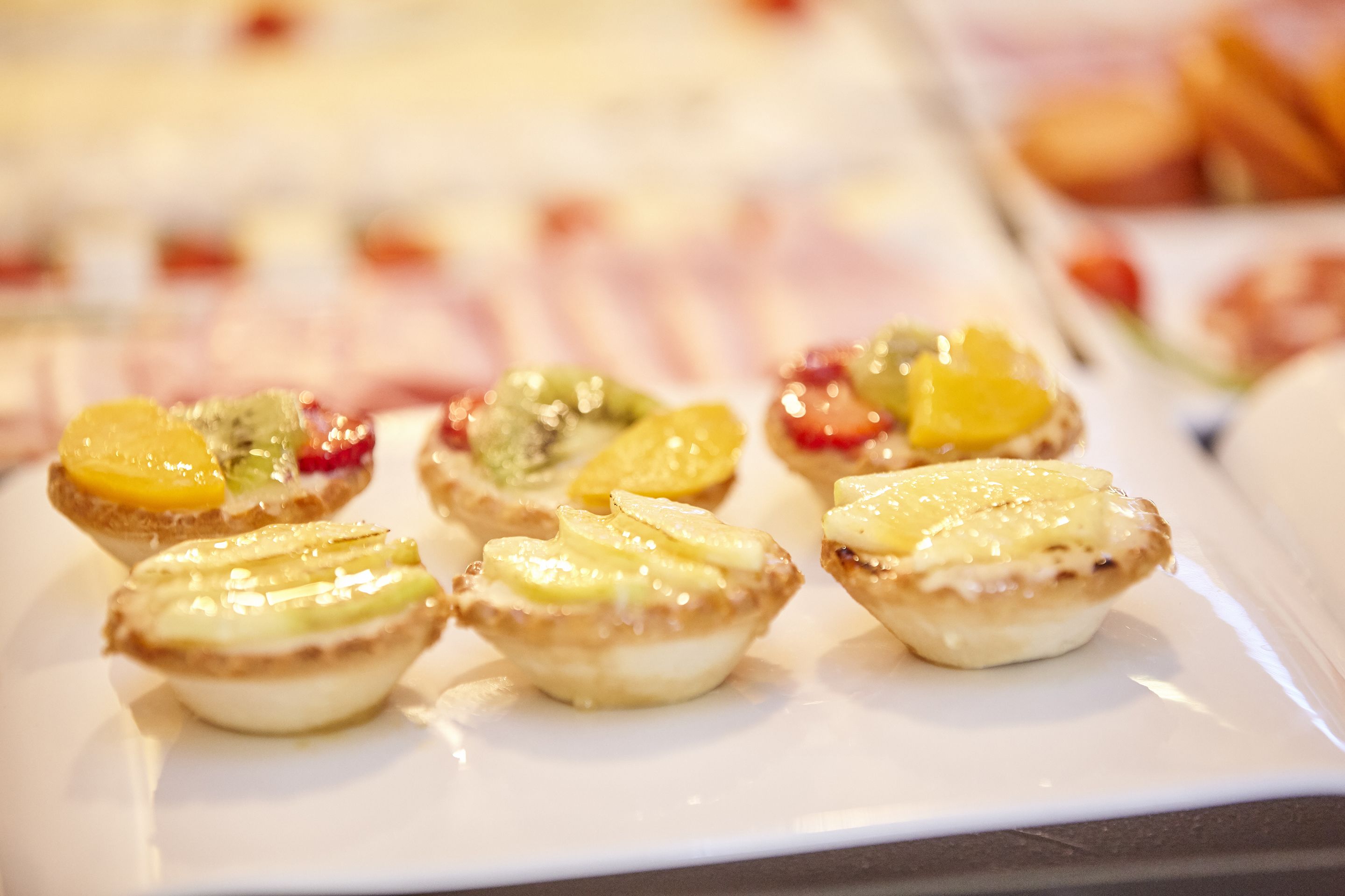 A plate of mini pastries with fruit toppings.