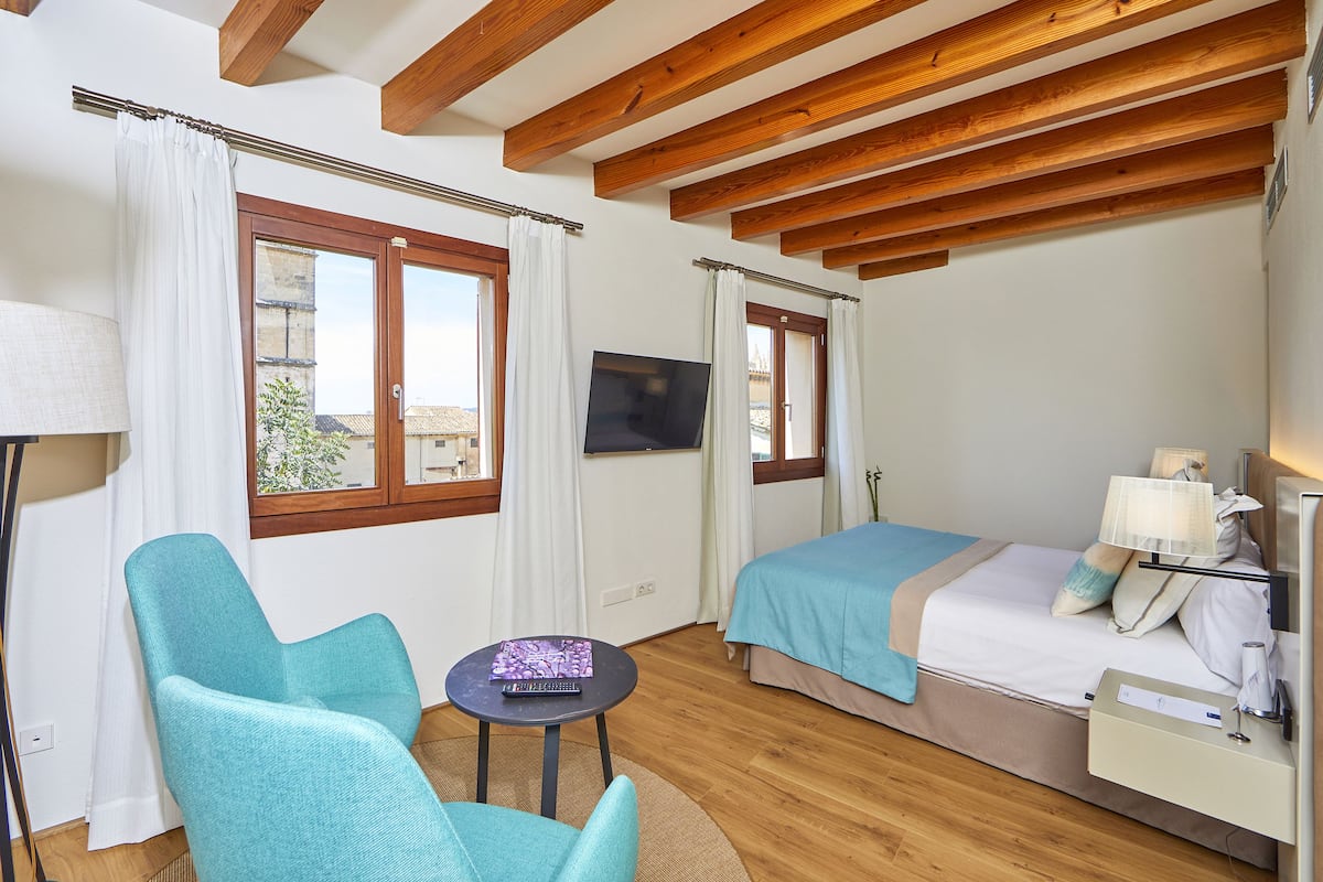 Ein Schlafzimmer mit zwei Betten, einem Fernseher, einem Sessel und einem kleinen Tisch.