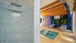Une salle de bain moderne dotée d’une douche à parois de verre et d’un espace piscine séparé avec des chaises longues.