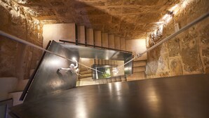 Un escalier avec une rampe métallique et une plateforme également dotée d’une rampe, menant à un niveau supérieur.