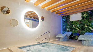 Un espace spa doté d’un jacuzzi, de poutres en bois au plafond et d’un mur végétal.
