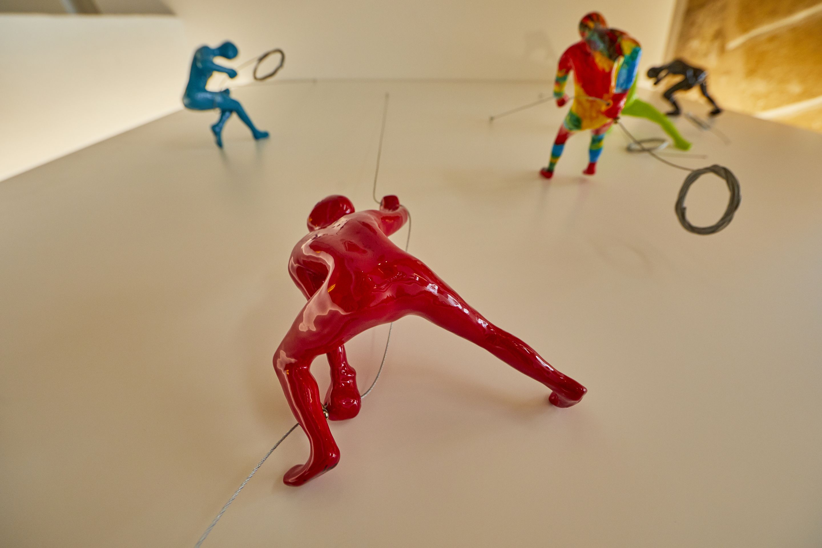 A white table with three abstract figures in red, blue, and multicolored attire.