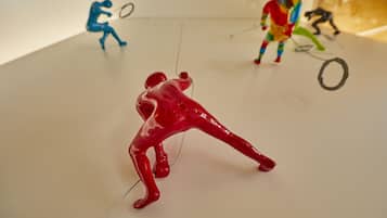 A white table with three abstract figures in red, blue, and multicolored attire.