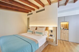A bedroom with a bed, bedside table, lamp, and a view of a bathroom.