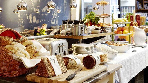 Een buffet met diverse gerechten, een broodrooster en een snijplank met brood.