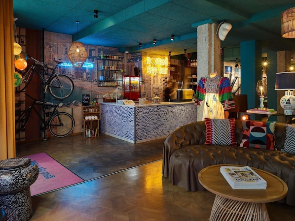 A bar area with a neon sign, a bicycle, and a cityscape mural. - 25hours Hotel The Trip (Frankfurt)