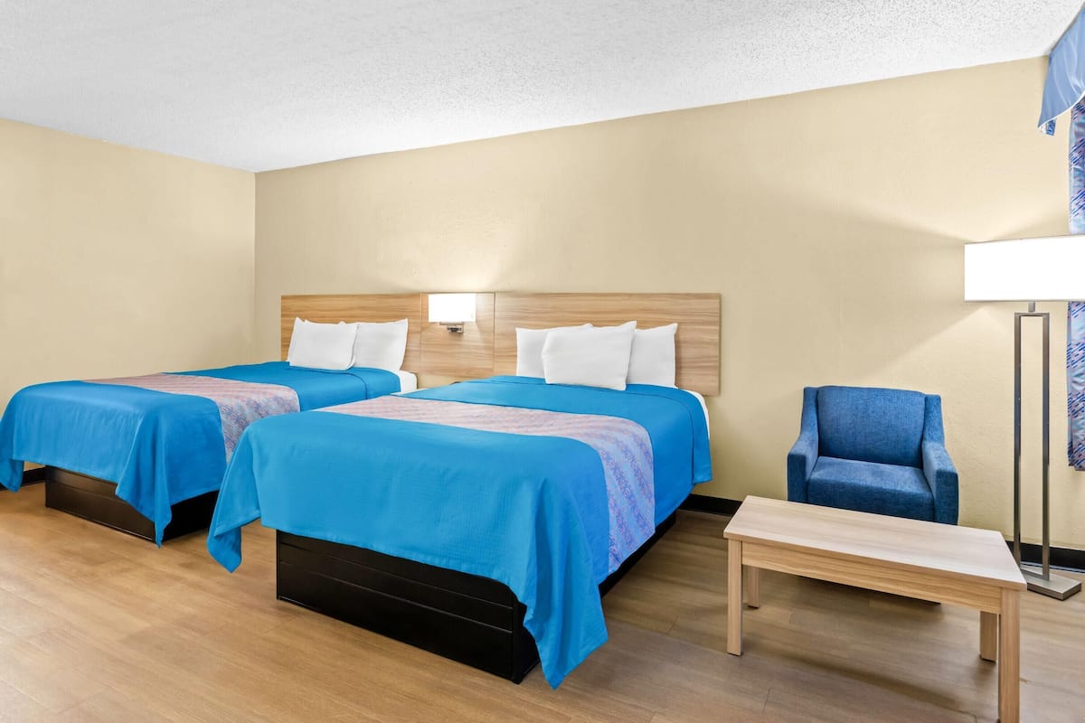 Une chambre d’hôtel avec deux lits, une chaise et une petite table.