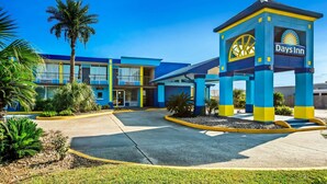 Un hotel Days Inn con una decoración azul y amarilla, que presenta una palmera y un cielo despejado.