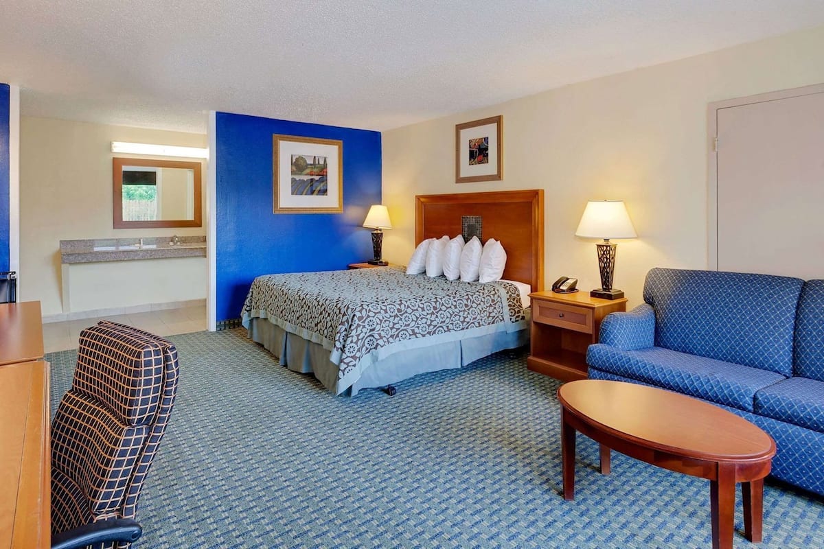 Une chambre d’hôtel avec un lit, un canapé, un bureau et une chaise.