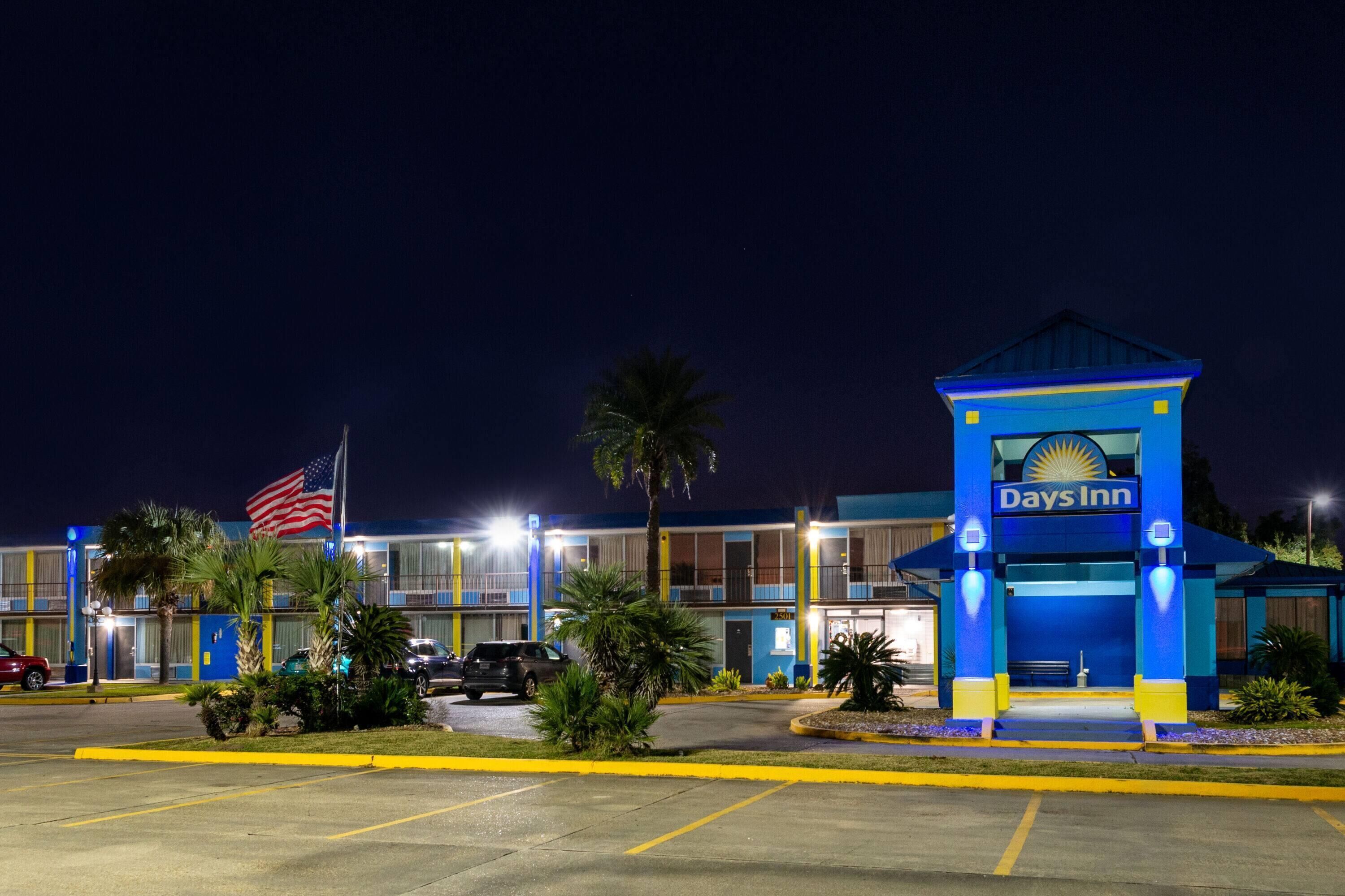 A Days Inn hotel with a blue entrance, American flag, and palm trees.