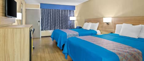 Habitación de hotel con dos camas, un escritorio, un televisor y la puerta del baño.