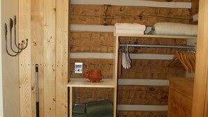 A wooden interior with a broom, shelves with towels, and a small heater. - Riverside Meadows Cabins (South Fork)
