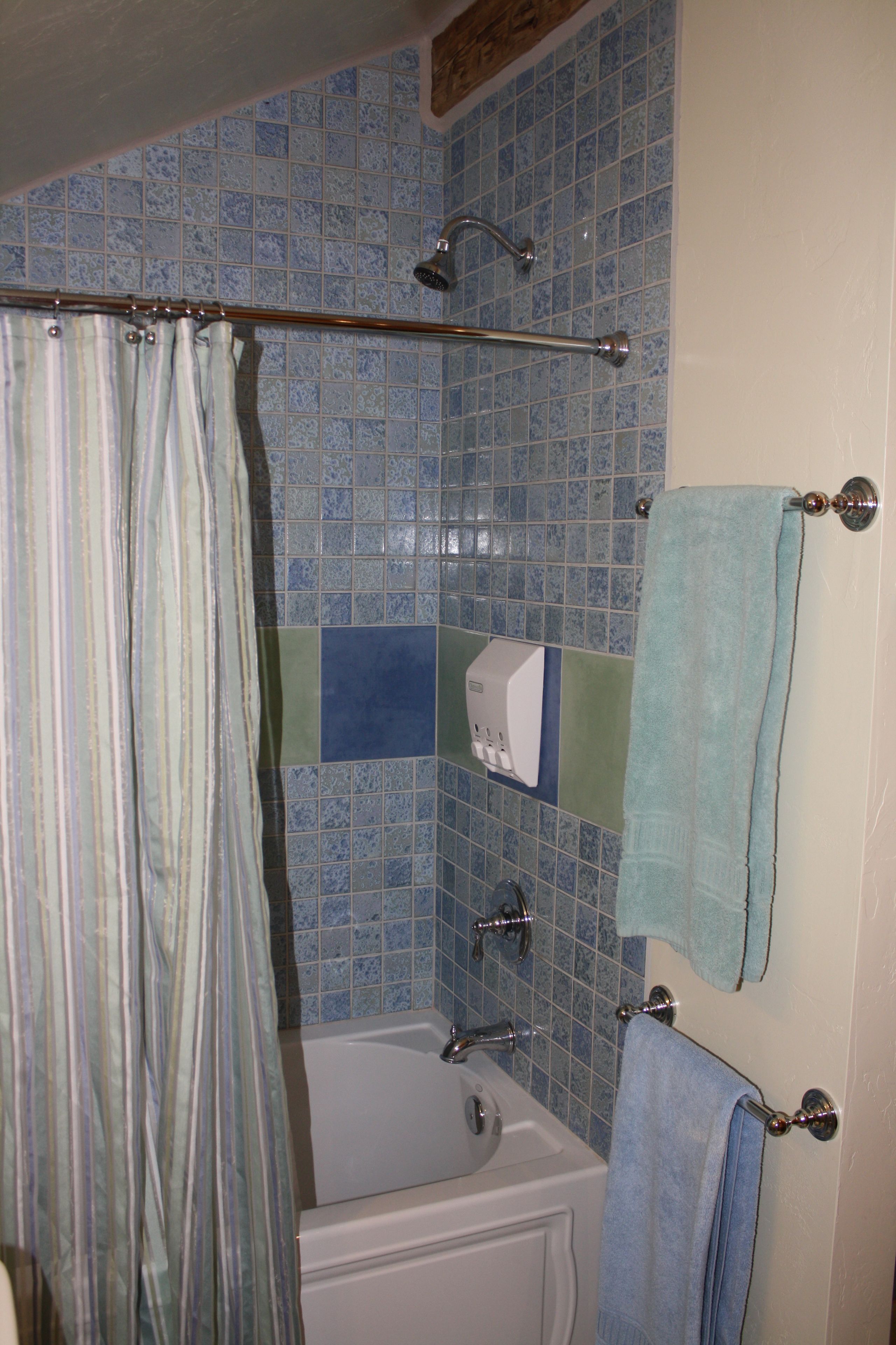 Ein Badezimmer mit Duschvorhang, einer Badewanne, einem Handtuchhalter mit Handtuch und einer Seifenspender.