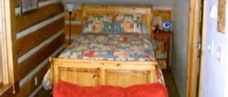 A bedroom with a wooden bed, a red chair, and a nightstand with a lamp.