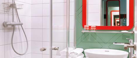 A modern bathroom with a glass-enclosed shower, a white sink, and a red-framed mirror.