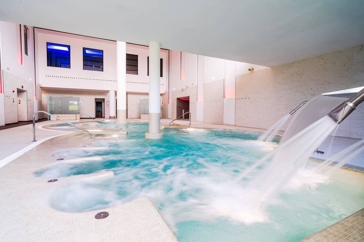 Ein großer Innenbereich mit Whirlpool, mehreren Sitzbereichen und einer Wasserspalt.