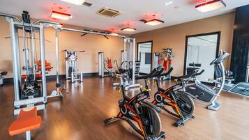 Uma academia com máquinas de cardio, equipamentos de musculação e um painel de espelhos.