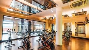 A gym with multiple exercise bikes and cardio machines, large windows, and a modern interior design. - URH Hotel Zen Balagares (Corvera de Asturias)