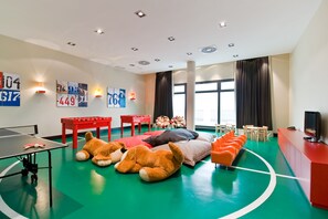 A room with a ping pong table, large stuffed animals, a foosball table, and a TV.