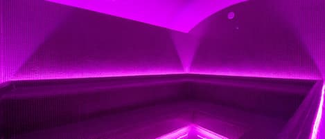 A modern spa with a geometric tile design and purple lighting.
