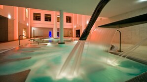 A spa area with a hot tub, a large pillar, and a wall with windows. - URH Hotel Zen Balagares (Corvera de Asturias)