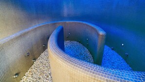 A spiral pool with blue tiles and pebbles, surrounded by a tiled wall. - URH Hotel Zen Balagares (Corvera de Asturias)