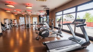 Un gimnasio con cintas de correr, elípticas y equipo de pesas.