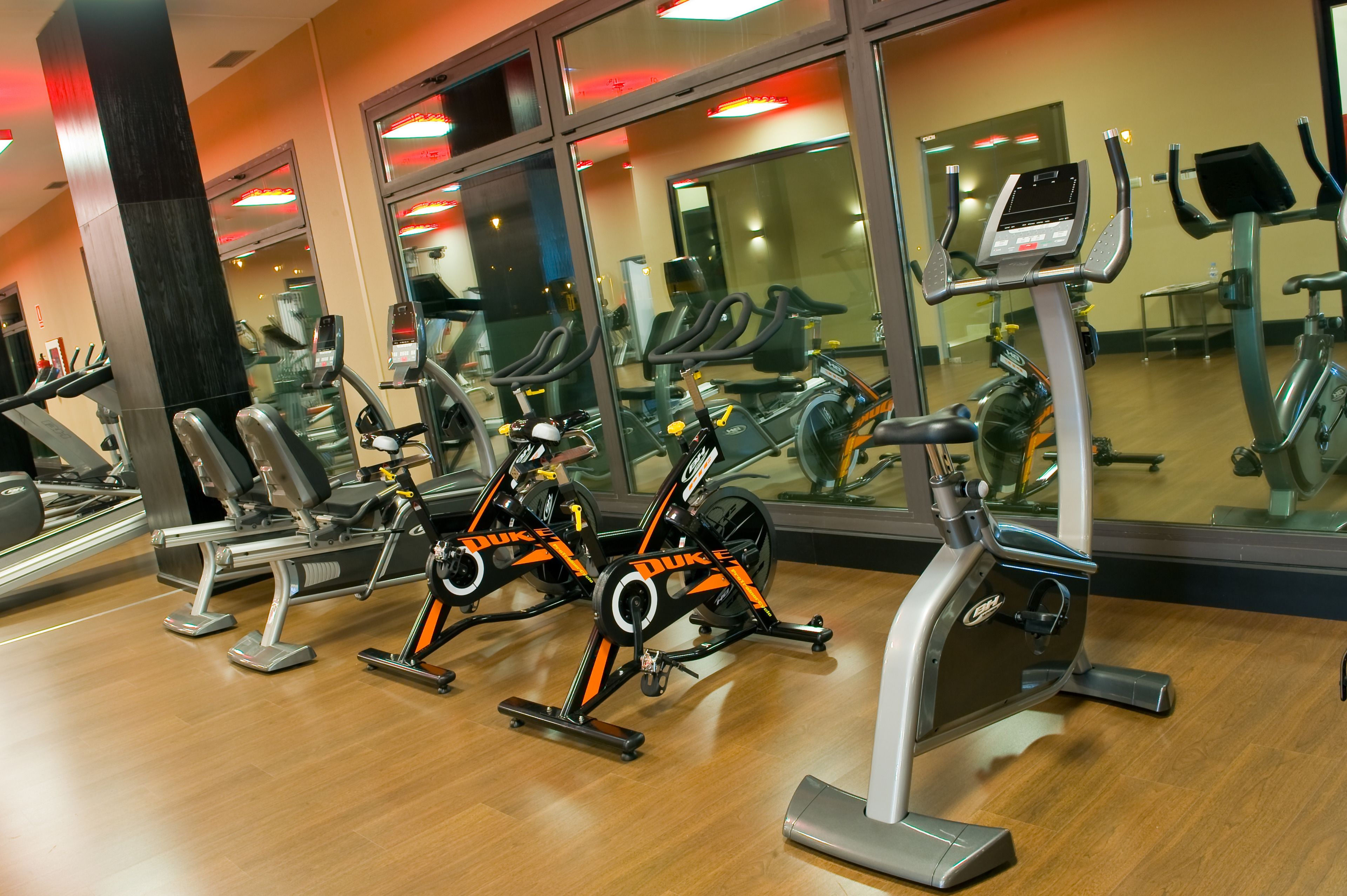 Une salle de sport équipée de vélos d’appartement, de tapis de course et d’autres appareils d’exercice.