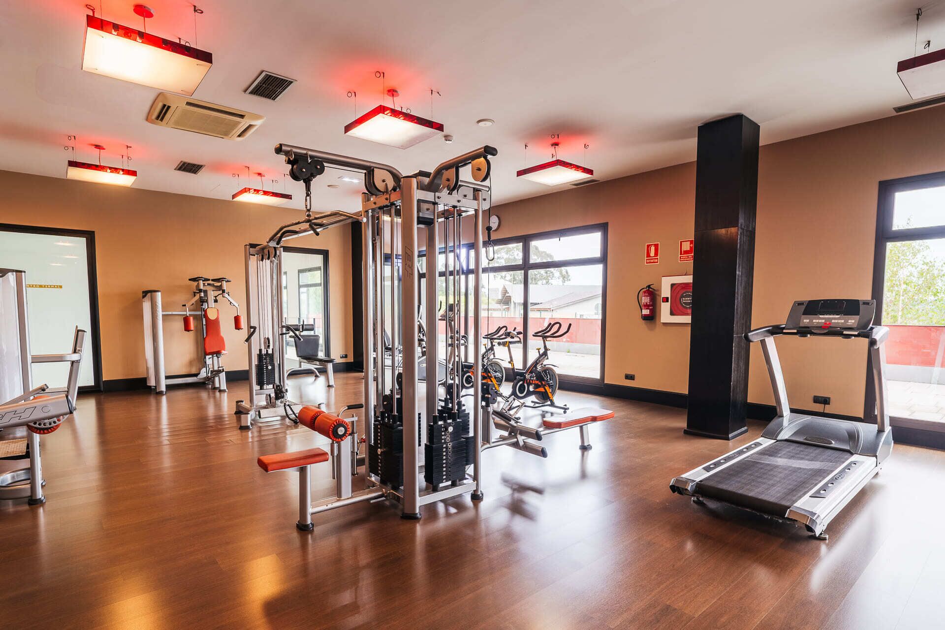 A gym with various exercise equipment, including a treadmill, stationary bikes, and weight machines.