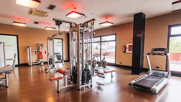Un gimnasio con diferentes equipos de ejercicio, como cintas de correr, bicicletas estáticas y máquinas de pesas.